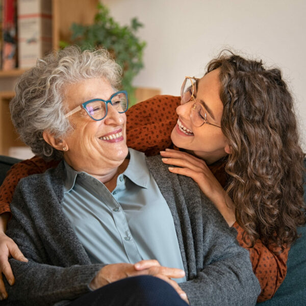 Grandmother and granddaughter laughing and embracing at home
